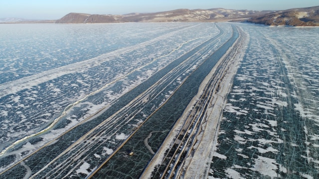 Sebuah kendaraan terlihat melintasi tepi Sungai Yenisei yang tertutup es selama musim dingin di Krasnoyarsk, Rusia. Foto: REUTERS/Ilya Naymushin