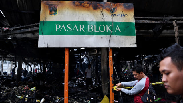 Seorang petugas kepolisian memasang garis polisi di lokasi kebakaran Tempat Penampungan Sementara Pasar Blok A, Kebayoran Baru, Jakarta Selatan, Rabu (6/3 Foto: ANTARA FOTO/Sigid Kurniawan