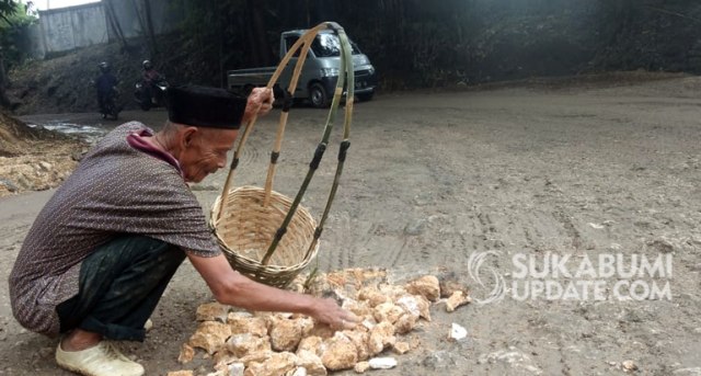 Ukat Sukatman, kakek berusia 80 tahun asal Kampung Ciembe, Desa Padabeunghar, Kecamatan Jampang Tengah, ini menambal lubang jalan dengan batu-batu kecil. Foto: Demmi Pratama