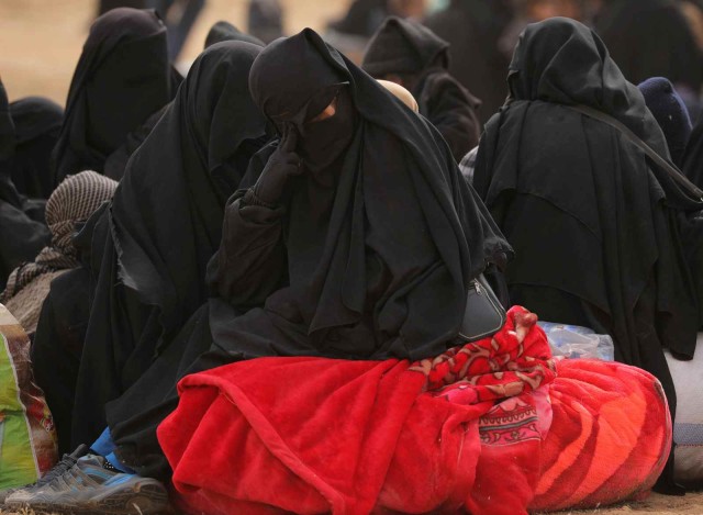 Seorang wanita duduk di atas selimut di dekat Baghouz. Foto: REUTERS / Rodi Said