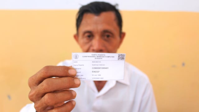 Sukirman Dakman, 52, menunjukkan kartu peserta Ujian Nasional Berbasis Komputer (UNBK), Minggu (3/3).   Foto : Tomy Pramono