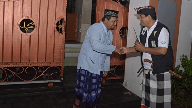 Pecalang atau petugas pengamanan adat Bali berjabat tangan dengan umat muslim yang selesai melakukan Salat Isya berjamaah saat melakukan patroli malam di wilayah Desa Adat Tuban. Foto: Antara/Fikri Yusuf