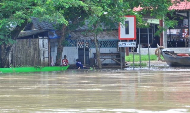 BAHAYA: Dua bocah sedang bermain di tepi bantaran Sungai Bengawan Solo Desa Banjarsari saat air sedang siaga II. 