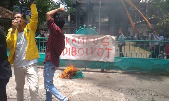 Mahasiswa memasang poster 'Kampus Diboikot' di pintu gerbang Kampus Universitas Darul Ulum (Undar) Jombang