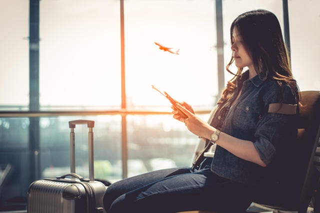 com-Ilustrasi seorang perempuan menggunakan smartphonenya di bandara Foto: Shutterstock
