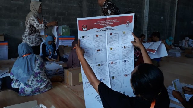 Warga sedang melipat dan menyortir surat suara untuk Pemilu 2019, di Gudang Penyimpanan Logistik KPU Yogyakarta, Rabu (13/3/2019). Foto: 