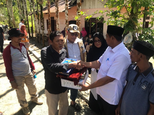Kadis Sosial, Alhudri menyerahkan bantuan kepada Kepala Desa Sikundo, saat mengunjungi kawasan terpencil itu. Foto: Dok. BPBA