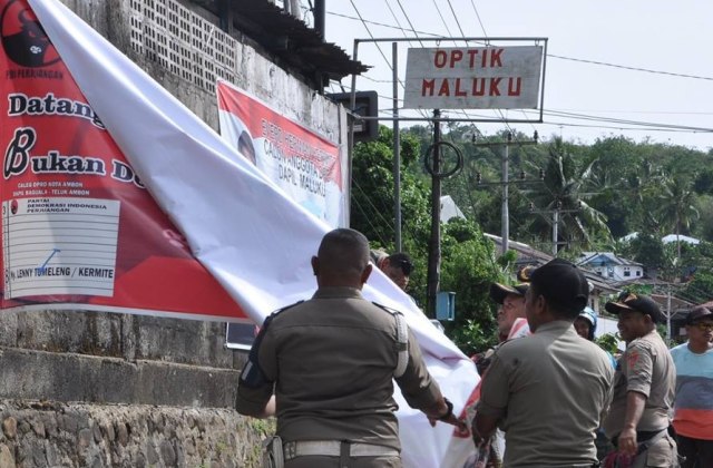 Petugas Bawaslu dan anggota Satpol PP menurunkan spanduk caleg di Ambon, beberapa waktu lalu (Foto: istimewa)
