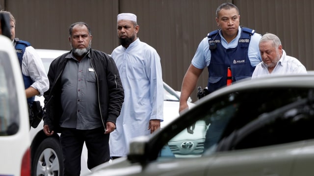 Polisi mengawal pria dari sebuah masjid di Christchurch, Selandia Baru, Jumat (15/3). Foto: AP Photo/Mark Baker