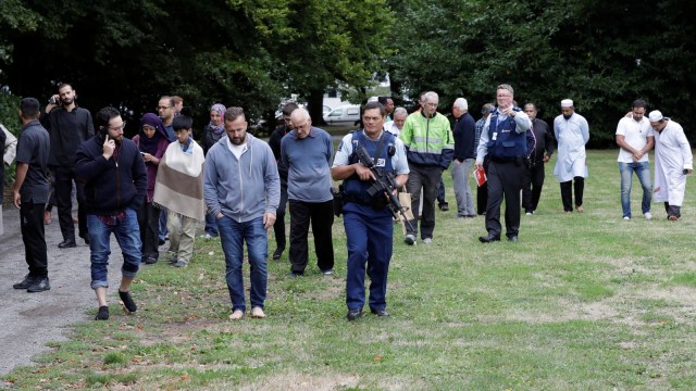 Polisi sedang mengawal orang-orang ke luar masjid di Christchurch, Selandia Baru. Foto: AP Photo/Mark Baker