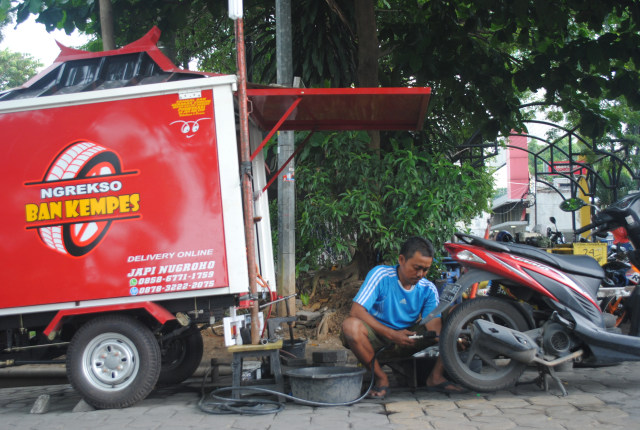 Jepi Nugroho, pemilik tambal online "Ngrekso Ban Kempes" sedang menambal ban sepeda motor yang bocor milik pelanggan di kawasan Jalan Slamet Riyadi, Solo, pada pada Jumat (15/3.2019). (Tara Wahyu N.V.)