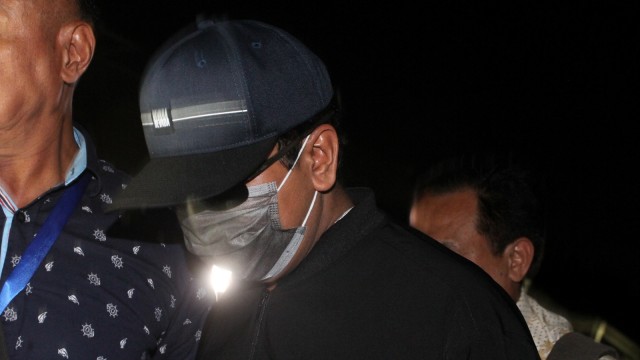 Ketua Umum Partai Persatuan Pembangunan (PPP) Romahurmuziy (mengenakan masker dan bertopi), digiring petugas saat tiba di Gedung KPK Merah Putih, Jakarta, Jumat (15/3). Foto: ANTARA FOTO/Reno Esnir