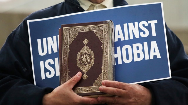 Seorang pria membawa tulisan "Bersatu Melawan Islamofobia" saat mengenang untuk para korban penembakan di masjid Christchurch, di luar balai kota di Toronto, Ontario, Kanada. Foto: Reuters/Chris Helgren