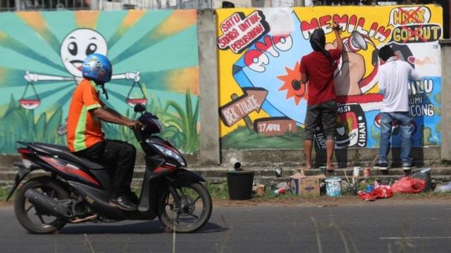 Para pelukis menggambar mural di dinding stadion Lampineung untuk sosialisasi Pemilu 2019, Banda Aceh, Minggu (17/3). Foto: Suparta/acehkini