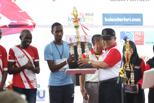 Pelari asal Kenya, Kiptoo, menerima trofi setelah berhasil menang pada Lari Maraton 11K Solo Open 2019 kategori internasional putra yang diselenggarakan pada Minggu (17/03/2019). (Agung Santoso)