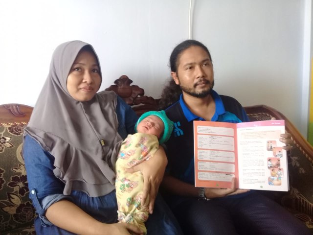 Jamal Haris (33) dan Riskiatun (32) menggendong putra keempatnya yang lahir diberi nama Sandiaga Uno, Senin (18/3/2019). (Ryan Hariyanto/MM).