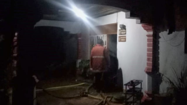 Petugas pemadam kebakaran saat berada di bagian depan rumah yang terbakar. Lantai dua sudah terbakar. (Foto: Rajid Duchlun/cermat