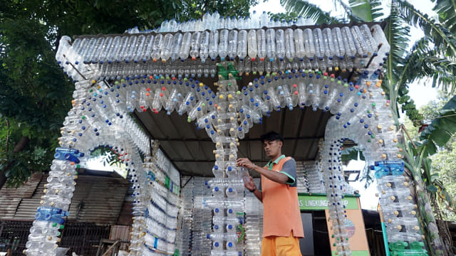 Petugas UPK Badan Air Dinas Lingkungan Hidup DKI Jakarta menata susunan sampah botol minuman plastik yang membentuk bangunan posko di kawasan Pasar Rebo, Jakarta, Selasa (21/3). Foto: Jamal Ramadhan/kumparan
