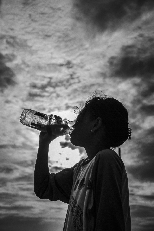 Anak meminum air minum ketika bermain di pesisir Cilincing, Jakarta Utara. Foto: Jamal Ramadhan/kumparan