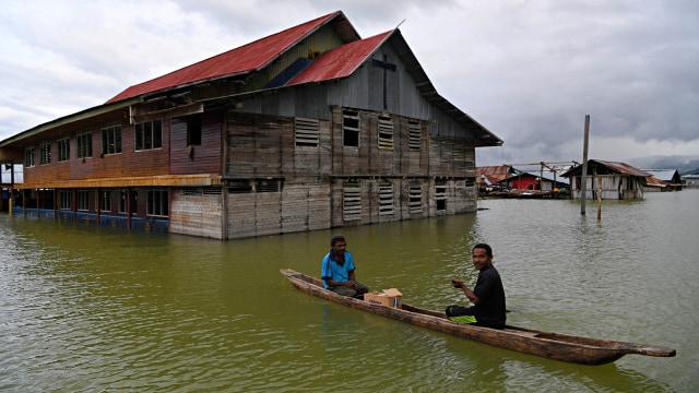 Warga menggunakan perahu melintas di samping gereja yang terendam banjir akibat meluapnya Danau Sentani dampak dari banjir bandang Sentani di Kampung Yoboi, Jaya Pura, Papua. Foto: Antara/Zabur Karuru
