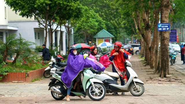 Sejumlah pengendara motor sedang mengenakan jas hujan di trotoar jalan raya, Hanoi, Vietnam. Foto: Nugroho Sejati/kumparan