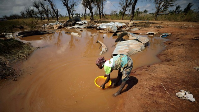 Seorang wanita mengumpulkan air untuk mencuci ketika air banjir mulai surut setelah Topan Idai, di Buzi dekat Beira. Foto: REUTERS / Mike Hutchings