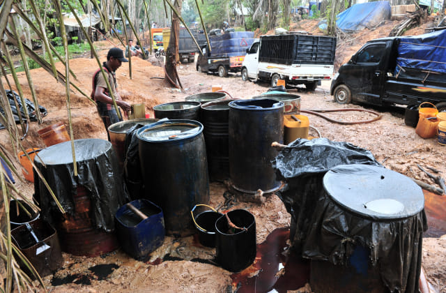 Warga memindahkan minyak mentah di lokasi pengeboran minyak ilegal, wilayah kerja pertambangan PT Pertamina (Persero), Taman Hutan Raya (Tahura) Sultan Thaha Syaifuddin, Jambi. Foto: ANTARA FOTO/Wahdi Septiawan