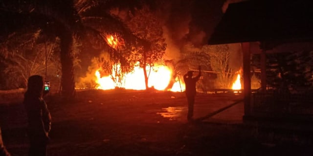 Seorang warga mengabadikan insiden kapal motor yang terbakar di dermaga Pasar Baru, Rasau Jaya, Kabupaten Kubu Raya, Selasa (26/3) dini hari. Foto: ist