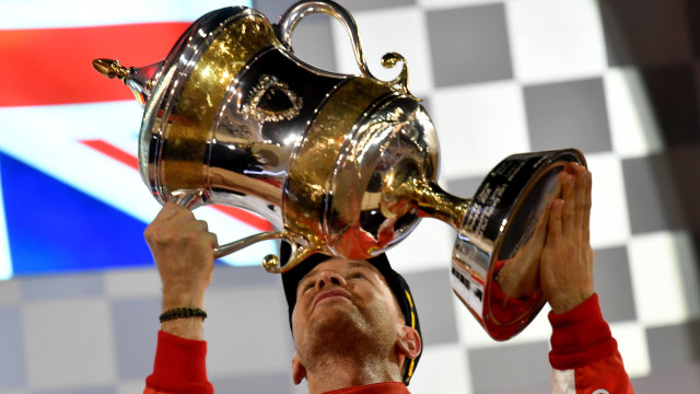 Sebastian Vettel mengangkat trofi kemenangannya di GP Bahrain 2018. Foto: Andrej Isakovic/AFP