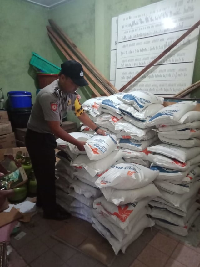 Salah satu petugas kepolisian membantu mengangkat beras