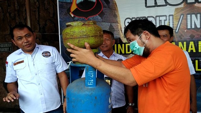 Pelaku menunjukkan cara mengoplos gas subsidi saat konferensi pers. Foto: Afiati Tsalitsati/kumparan