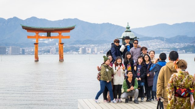 Rombongan wisatawan berfoto bersama di depan gerbang mengapung yang populer di Hiroshima Foto: Shutter Stock