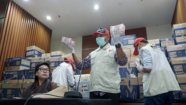 Petugas memegang sejumlah barang bukti berupa uang tunai Rp 100 ribu pada konferensi pers terkait dugaan suap pengiriman pupuk via kapal di Gedung KPK, Jakarta, Kamis, (28/3). Foto: Jamal Ramadhan/kumparan