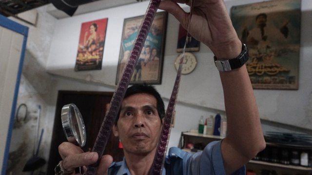 Firdaus memeriksa kondisi film di Sinematik Indonesia, Jakarta. Foto: Iqbal Firdaus/kumparan