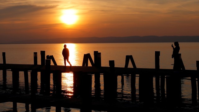 Sejumlah wisatawan berkunjung saat matahari terbenam di danau Nuesiedl, Podersdorf, Austria. Foto: Reuters/Leonhard Foeger