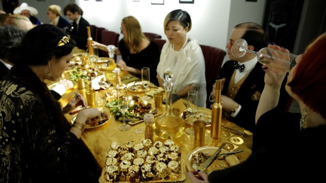 Sejumlah pengunjung menikmati hidangan makanan yang dibalut dengan emas 24 karat di Paris, Prancis, (28/3). Foto: REUTERS / Philippe Wojazer