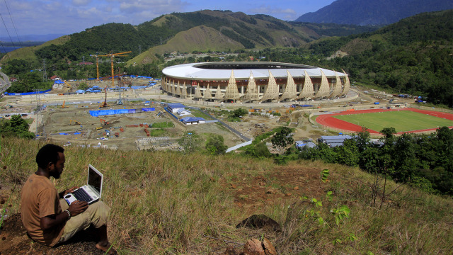 Warga menyaksikan proses pembangunan Kompleks Stadion Papua Bangkit di Distrik Sentani Timur. Foto: ANTARA FOTO/Gusti Tanati