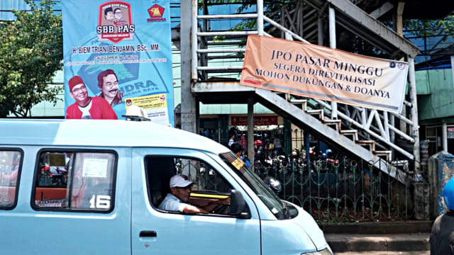 Angkutan umum melewati spanduk pemberitahuan tentang revitalisasi JPO Pasar Minggu. Foto: Iqbal Firdaus/kumparan