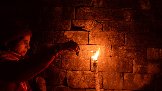 Sorang warga menyalakan lampu tempel. Foto: AFP