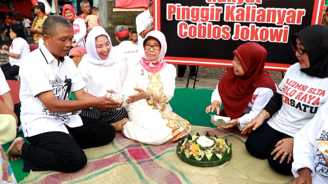 Ibunda Presiden Joko Widodo, Sudjiatmi, menerima potongan tumpeng saat acara doa bersama & kenduri massal di pinggir Jembatan Kalianyar, Kecamatan Banjarsari, Solo, pada Senin (8/4/2019).  (Fernando Fitusia)