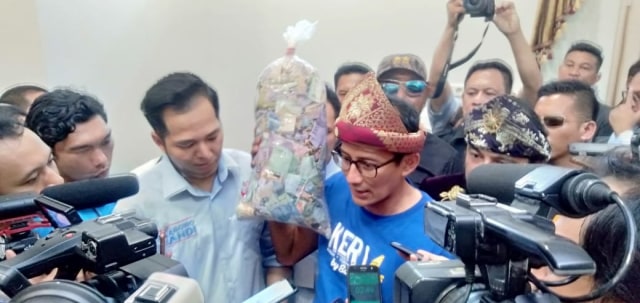 Cawapres nomor urut 02, Sandiaga Uno, memperlihatkan kantong plastik berisi uang kepada awak media di Palembang (Urban Id)