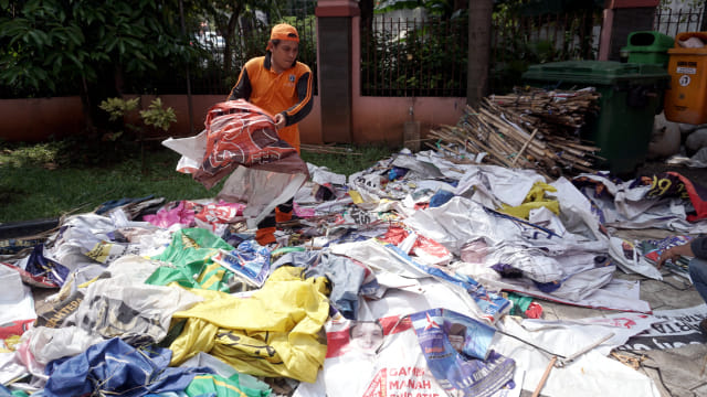 Petugas merapihkan Alat Peraga Kampanye (APK) pada minggu tenang di Jakarta. Foto: Iqbal Firdaus/kumparan