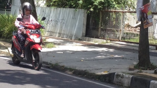 Pengendara motor melintas di depan atribut kampanye yang belum dibersihkan di Jalan Palasari, Kota Bandung. (Iman Herdiana)