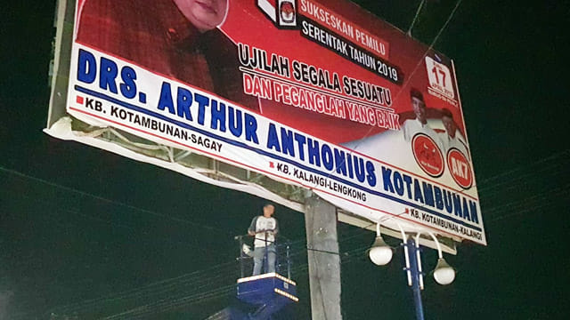 Petugas Bawaslu Kota Manado tengah berdiri di atas crane untuk melakukan penurunan alat peraga kampanye (APK) yang masih terpasang di sejumlah titik di Kota Manado