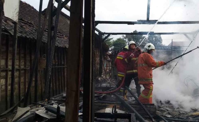 Petugas memadamkan api yang membakar rumah Supriatun