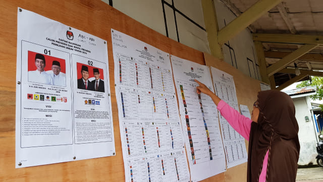 Seorang warga melihat papan pengumuman di satu diantara TPS di Pontianak, Rabu (17/4). Foto: Daddy Cavalero