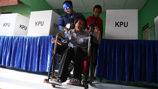 Petugas KPPS melayani warga yang akan memberikan hak suaranya di TPS 5 Pondok Benowo Indah yang bertema super hero di Surabaya. Foto: ANTARA FOTO/Zabur Karuru