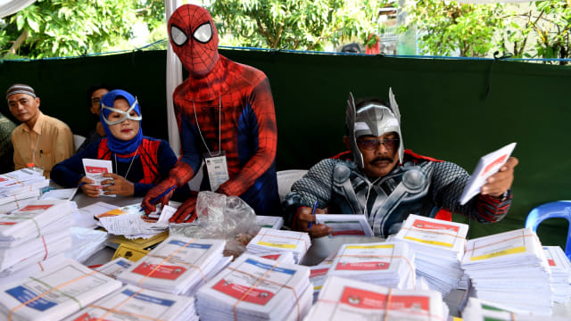 Petugas KPPS melayani warga yang akan memberikan hak suaranya di TPS 5 Pondok Benowo Indah yang bertema super hero di Surabaya, Jawa Timur, Rabu (17/4). Foto: ANTARA FOTO/Zabur Karuru