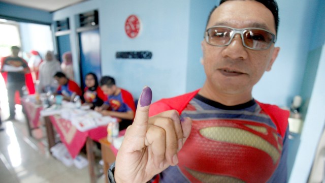 Petugas KPPS menunjukan jari seusai memberikan hak suaranya di TPS 072 Mekarjaya yang bertemakan superman di Depok, Jawa Barat, Rabu (17/4). Foto: ANTARA FOTO/Yulius Satria Wijaya