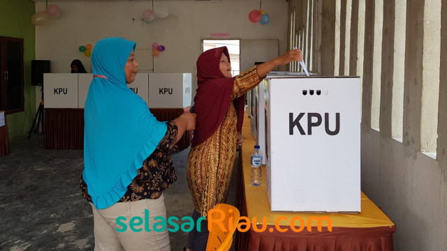 PETUGAS KPPS mengarahkan pemilih untuk memasukkan surat suara sesuai dengan kotaknya. 